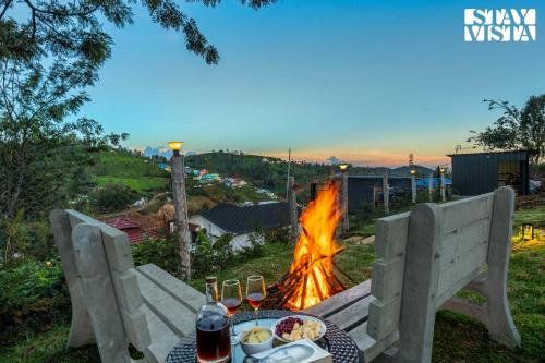 a table with food and drinks next to a fire at StayVista at Rustling Pine with Bonfire, BBQ & Lawn in Ooty