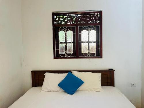 a bed with two pillows and a window at Malmika Villa in Ahangama