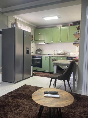 una cocina con armarios verdes, una mesa y un refrigerador en Harmony House, en Tirana