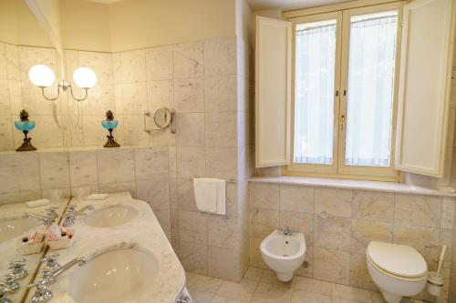 a bathroom with two sinks and a toilet and a window at Hotel San Luca in Spoleto