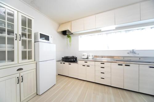 a kitchen with white cabinets and a white refrigerator at Miraie Kuwana Shimofukayabe 2 in Kuwana