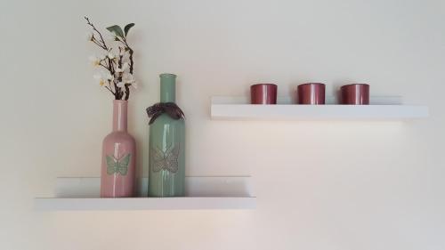 a white shelf with vases and cups on it at Design Apartment nähe Düsseldorf in Krefeld