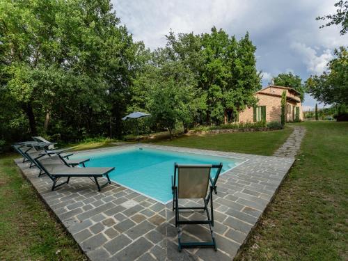 a swimming pool with several chairs and a table at Villa with Panoramic Views in Marciano