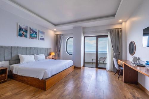 a bedroom with a bed and a desk and windows at Maris Beach Hotel Phu Quoc in Phu Quoc