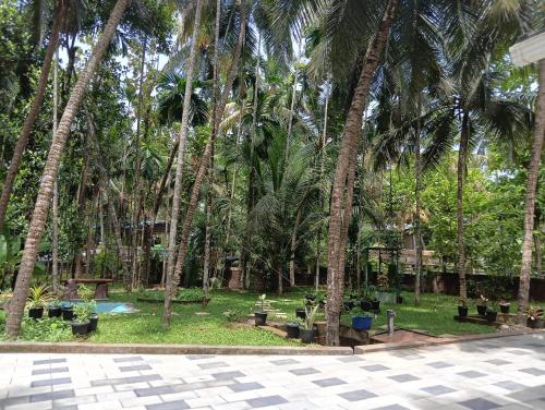 a park with palm trees and a pool at Gurukripa Homestay in Kānnangād