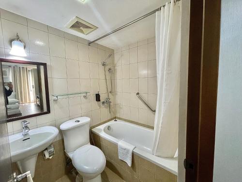 a bathroom with a toilet and a tub and a sink at CEO Flats in Manila