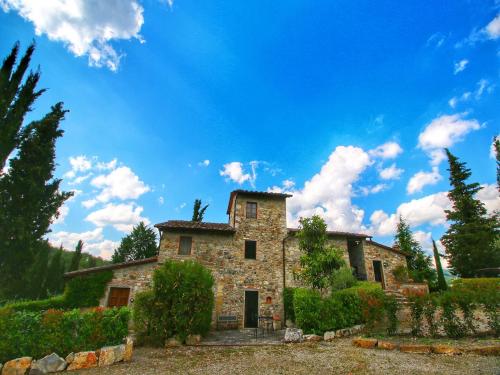 an old stone house with trees and a blue sky at Pretty farmhouse with terrace in Radda in Chianti