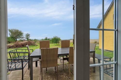 a patio with a table and chairs and a window at Idyllic Country House With Sea View And Sunsets in Rønne