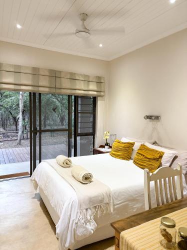 a bedroom with a large white bed with yellow pillows at InniBos Marloth Park in Marloth Park