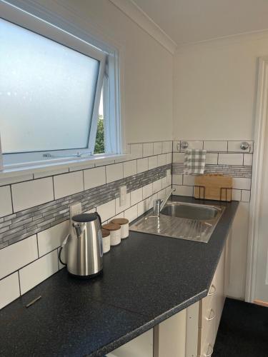 Una encimera de cocina con un fregadero y una ventana. en Modern guesthouse right in town, en Motueka