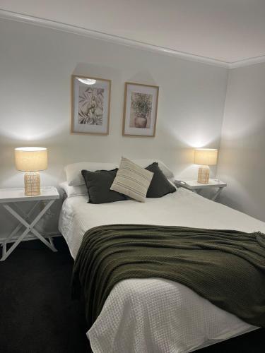 Un dormitorio con una cama grande con dos mesas y dos lámparas. en Modern guesthouse right in town, en Motueka