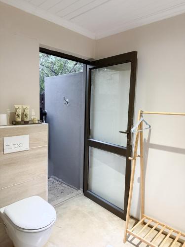 a bathroom with a toilet and a sliding glass door at InniBos Marloth Park in Marloth Park
