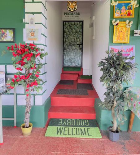 a welcome sign in front of a building with red stairs at Pug Mark Jungle Resort - Masinagudi in Masinagudi