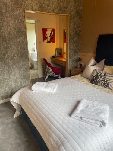 a bedroom with a large white bed with a mirror at Lilac Lodge Retreat - set in its own acre of land in Otley