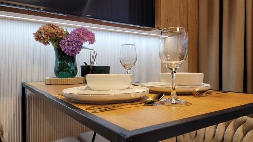 a table with plates and glasses and a vase of flowers at Smart Apart 8 - Apartament Kielce, rynek, main square, centrum, targi, FV in Kielce