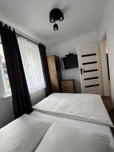 a bedroom with a white bed and a window at Willa Gazda Apartamenty in Sromowce Niżne