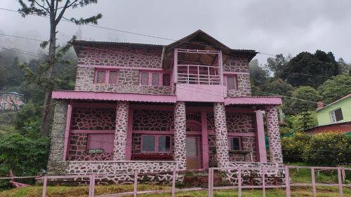 a pink house with a balcony on top of it at Pink House Vattakanal Kodaikanal in Kodaikānāl