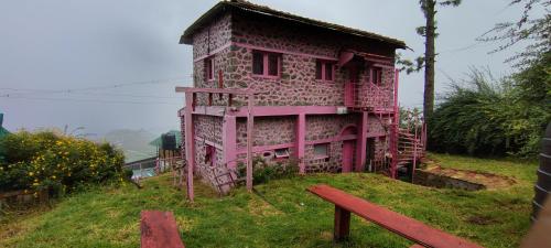 a pink building on top of a hill with a bench at Pink House Vattakanal Kodaikanal in Kodaikānāl