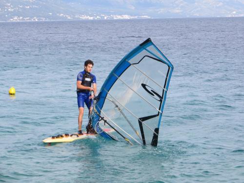 a man standing on a surfboard with a sail at Apartmani Lučica in Mimice