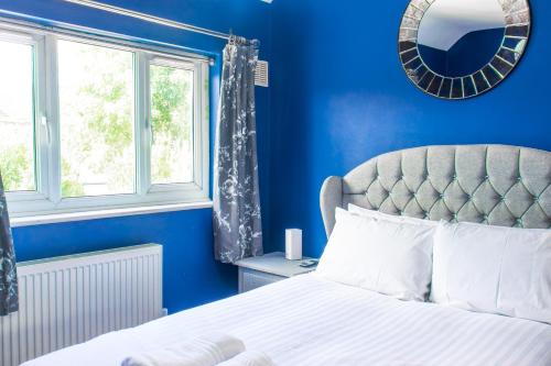 a blue bedroom with a bed and a window at Stunning Family Home nr London Harry Potter Tour Pass The Keys in Borehamwood