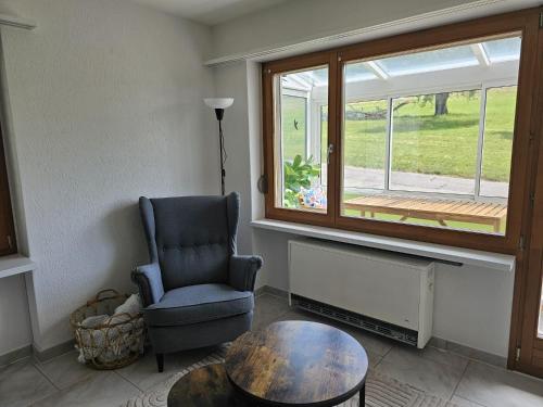 a living room with a chair and a table and a window at Apartment Hügelruhe Mandach - 100 m2 - 3 Schlafzimmer - Ferien - Business in Böttstein