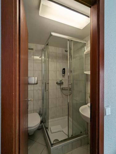 a bathroom with a shower and a toilet and a sink at A - City HOTEL Schiff in Rastatt