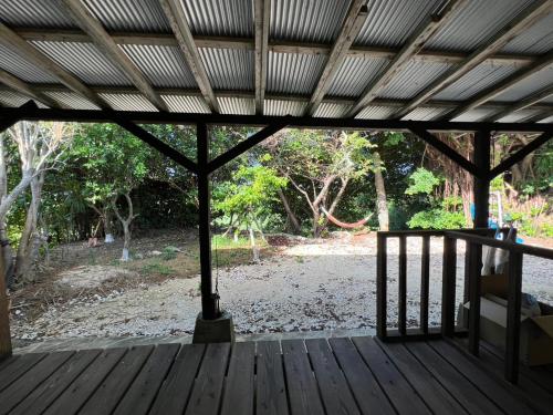 a porch with a wooden deck with a roof at Hostel あざみ庵よろん in Yoron
