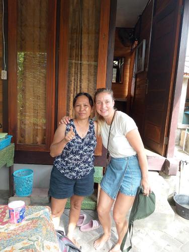 two women are standing outside of a house at Naca Homestay in Manado