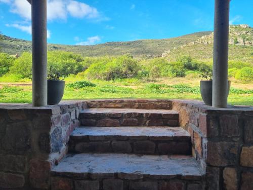 a stone stairway with two columns and a field with hills at Lambertshoek Farm Stay in Graafwater