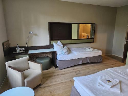 Cette chambre comprend deux lits, une chaise et un miroir. dans l'établissement Schulungszentrum Töplitz, à Leest