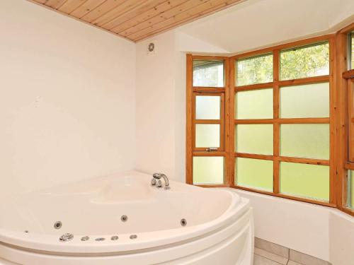 a white bathroom with a tub and a window at 8 person holiday home in Læsø in Læsø