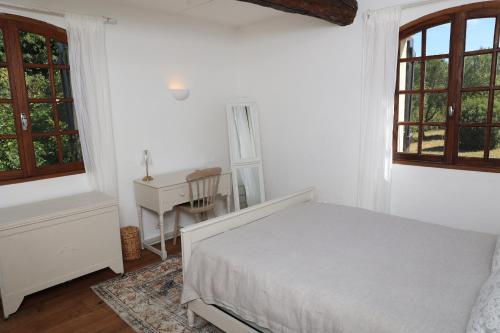 a bedroom with a bed and a desk and windows at Pure Gardères in Monlezun