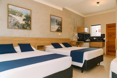 a hotel room with two beds and a kitchen at Marmeu Tombo in Guarujá
