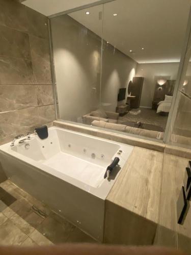 a bathroom with a large tub with a mirror at شقق ثري ستار للشقق المخدومة in Al Kharj
