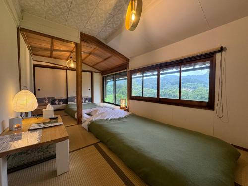 a bedroom with two beds and a desk and windows at Osugi-ya 大杉屋 in Wazuka