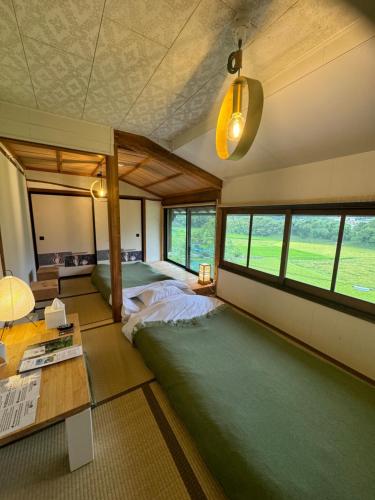 a bedroom with two beds and a table and windows at Osugi-ya 大杉屋 in Wazuka