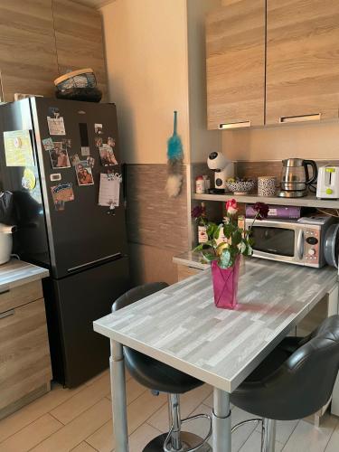 a kitchen with a table with chairs and a refrigerator at Maison chaleureuse proche du circuit des 24h et autoroute in Écommoy