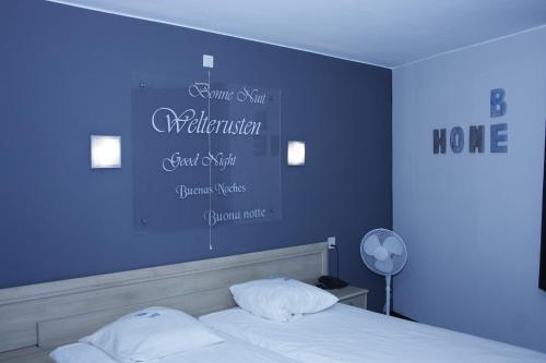 a bedroom with a blue wall with a bed with white pillows at Hotel & Appartementen Royal in Sas van Gent