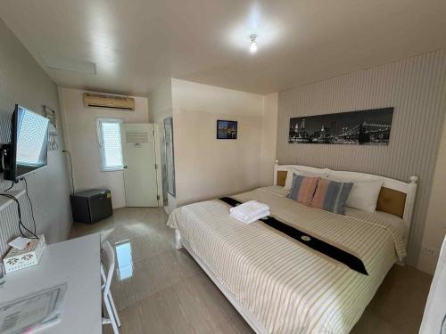 a bedroom with a bed and a television in it at Home JANO in Cha Am