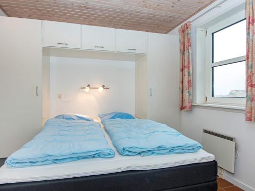 a bed with blue sheets in a room with a window at 6 person holiday home in Fanø-By Traum in Fanø