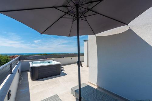 a patio with an umbrella and a tub on a balcony at Penthouse Stella Marini with jacuzzi and sea view 2,5 km from sea in Tar