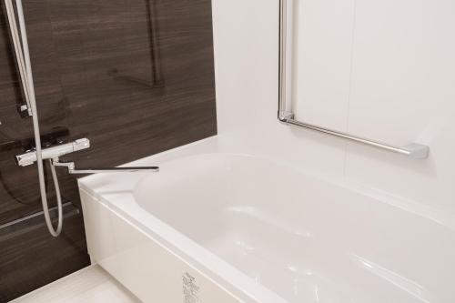 a white bath tub in a bathroom with a shower at The LOFT INN FUKUOKA in Fukuoka
