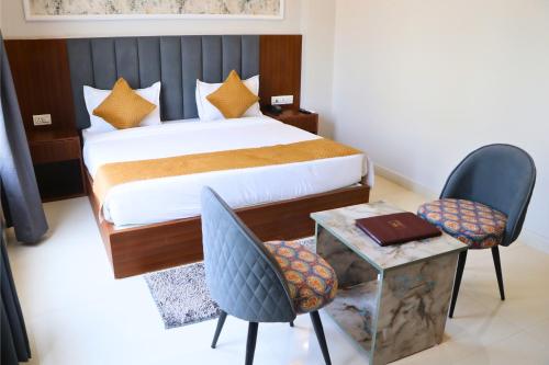 a bedroom with a bed and two chairs and a table at The Aurum Park Haridwar in Kankhal