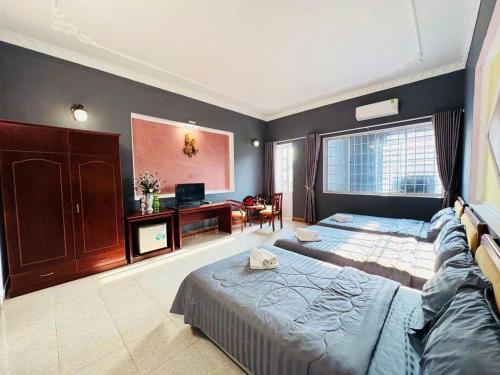 a bedroom with two beds and a television in it at The Warm khách sạn bãi sau giá rẻ in Vung Tau