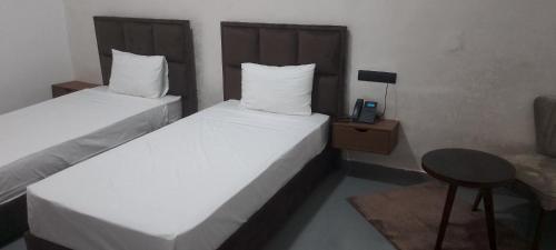 two beds in a room with a table and a phone at Hotel De Provence in El Jadida
