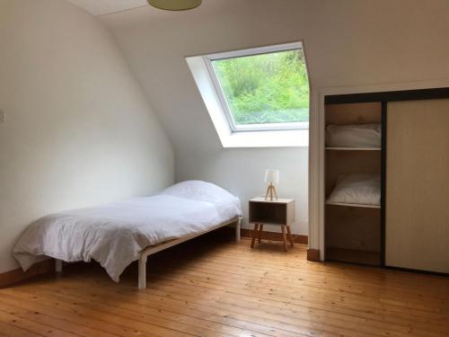 a bedroom with a bed and a window in a attic at Gîte Ar Boutilh in Ploulech