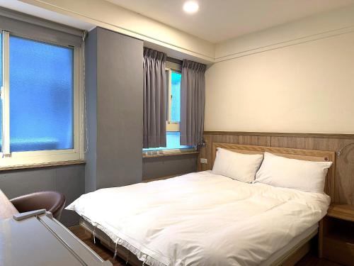 a bedroom with a white bed with two windows at 新獅城商務旅館New Lion City Hotel in Taipei
