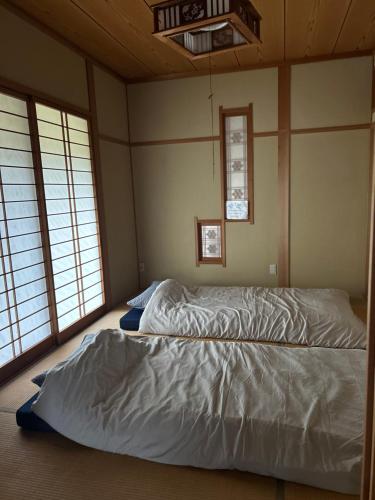 伊万里市にある1日1組様限定アスパラの収穫体験と庭でバーベキューが楽しめる民宿うめむらの窓が2つある部屋にある大きなベッド