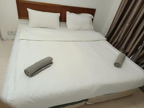 a large white bed with a remote control on it at My Getaway Home @Marina Cove in Lumut