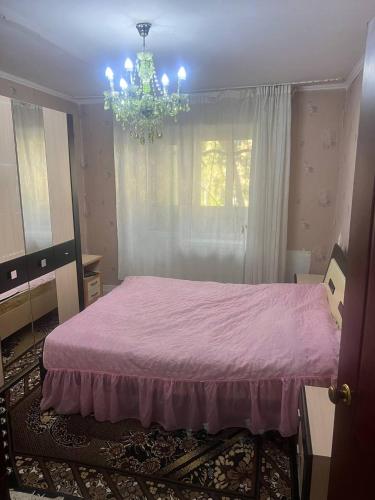 a bedroom with a pink bed and a chandelier at Karakol City Center in Karakol